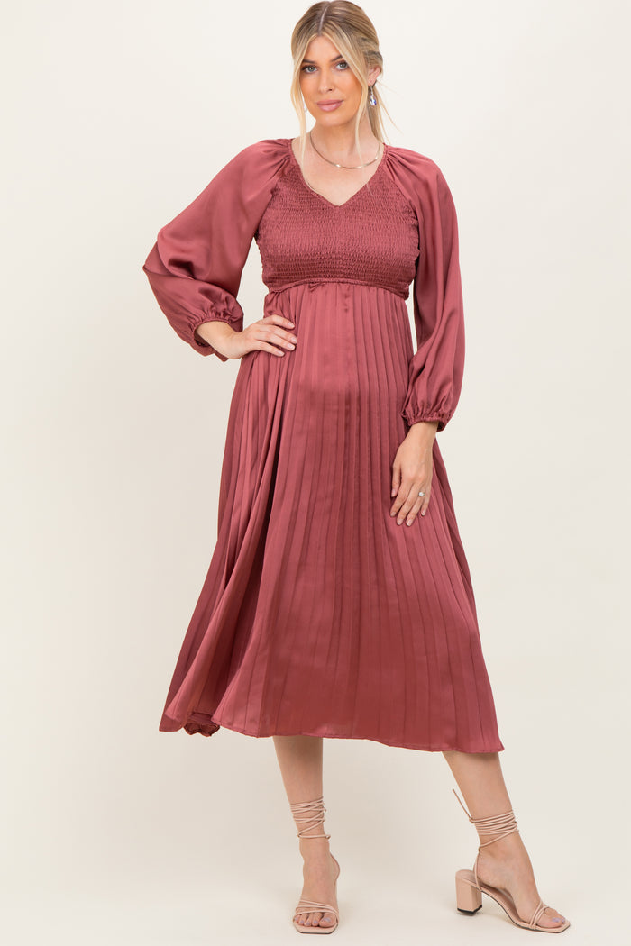 woman wearing a rust-colored pleated midi dress with smocked bodice and puff sleeves