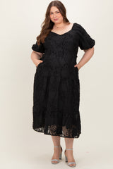 woman wearing a black puff sleeve maxi maternity dress with a textured floral design and pockets
