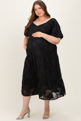 woman wearing a black maternity plus dress with floral detailing, cradling her baby bump