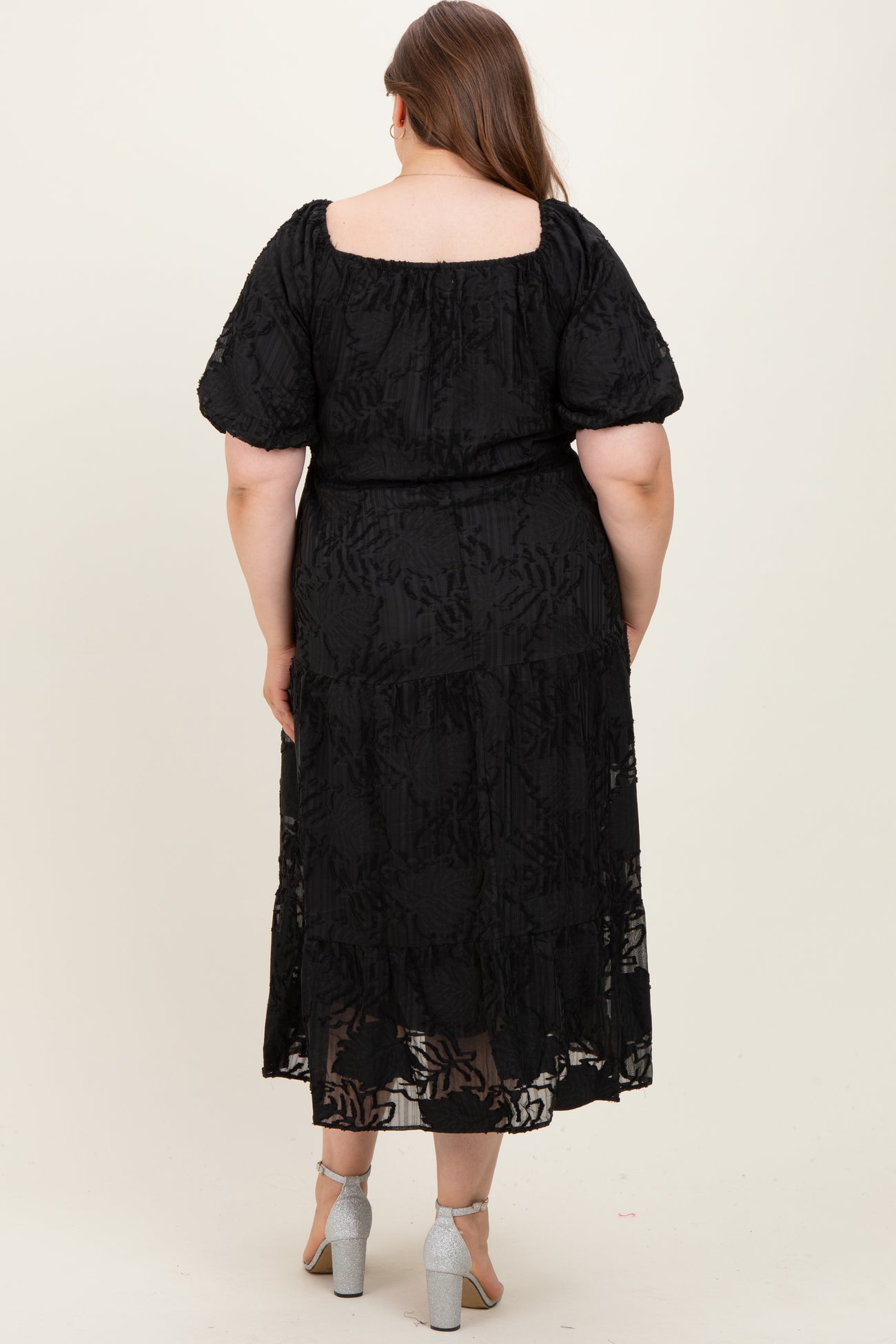 maternity plus model wearing a black floral lace maxi dress with short puff sleeves and a tiered skirt