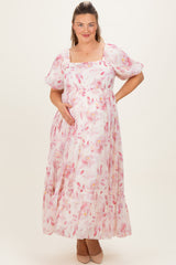 woman wearing a pink floral maternity maxi dress and gently cradling her baby bump