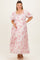 woman wearing a pink floral maternity maxi dress and gently cradling her baby bump