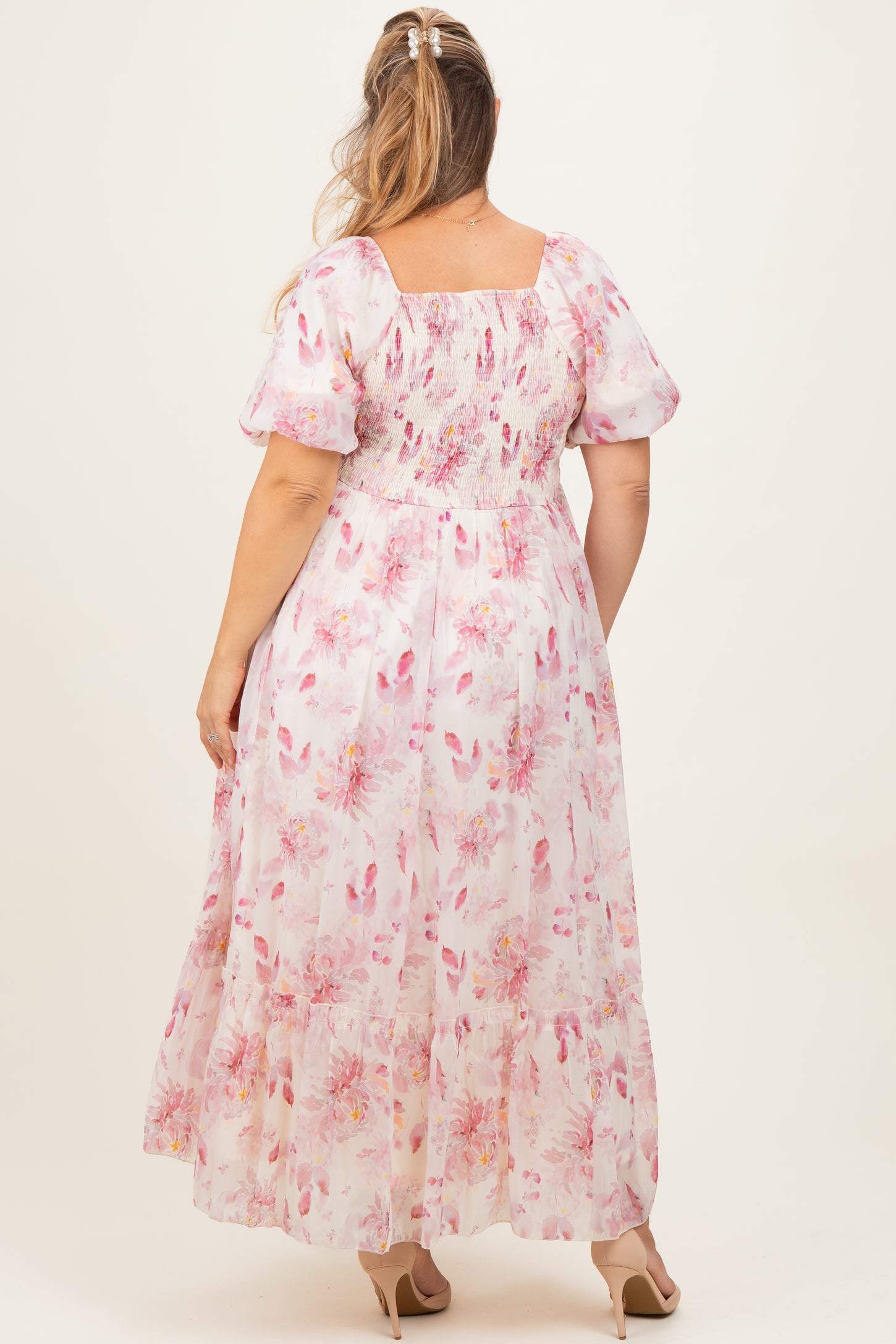 woman wearing a floral pink maternity plus maxi dress with puffed sleeves, showing the back view