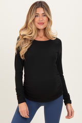 woman wearing a black long sleeve maternity top with ruching and showing her baby bump
