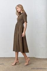 woman wearing a brown gingham midi dress with a smocked bodice and short sleeves, paired with nude heeled sandals