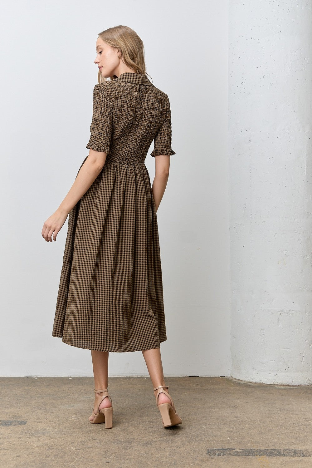woman wearing a short sleeve brown checked midi dress with a fitted bodice and flared skirt, seen from the back