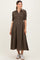 woman wearing a brown checked maternity dress with a button-down front and smocked bodice, holding her baby bump