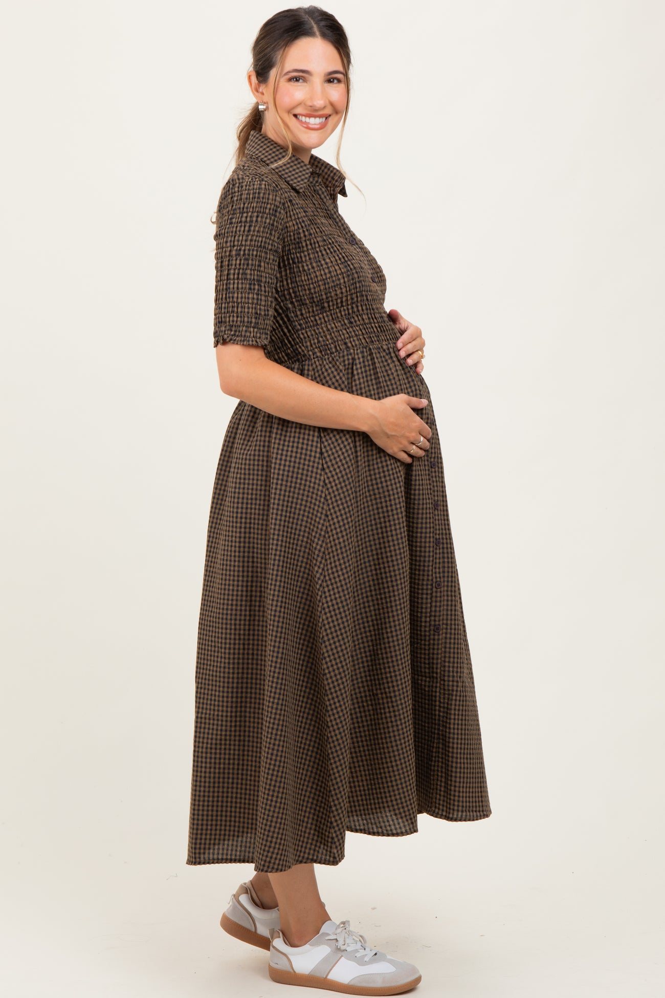 woman wearing a brown checkered maternity dress and holding her baby bump