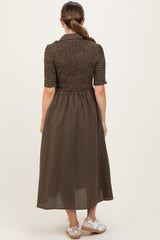 woman wearing a brown checkered maternity dress with a smocked bodice and short sleeves, shown from the back