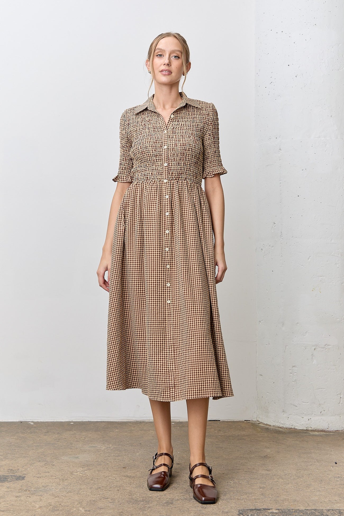 woman wearing a brown and beige checkered midi dress with short puff sleeves and a button-down front