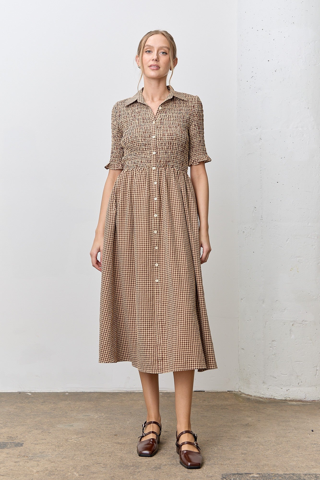 woman wearing a brown and beige checkered midi dress with short puff sleeves and a button-down front