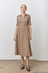 woman wearing a brown and beige checkered midi dress with short puff sleeves and a button-down front