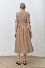 woman wearing a brown and cream checkered midi dress with short sleeves and a smocked back detail