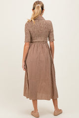 woman wearing a brown and cream checkered maternity dress with a smocked bodice and mid-calf length