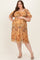 woman wearing a mustard yellow floral embroidered maternity dress with puff sleeves and a visible baby bump