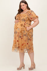 woman wearing a mustard yellow floral embroidered maternity dress with a cinched waist and puff sleeves, showing her baby bump