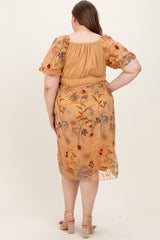 woman wearing a mustard yellow maternity plus dress with floral embroidery and puff sleeves, viewed from the back