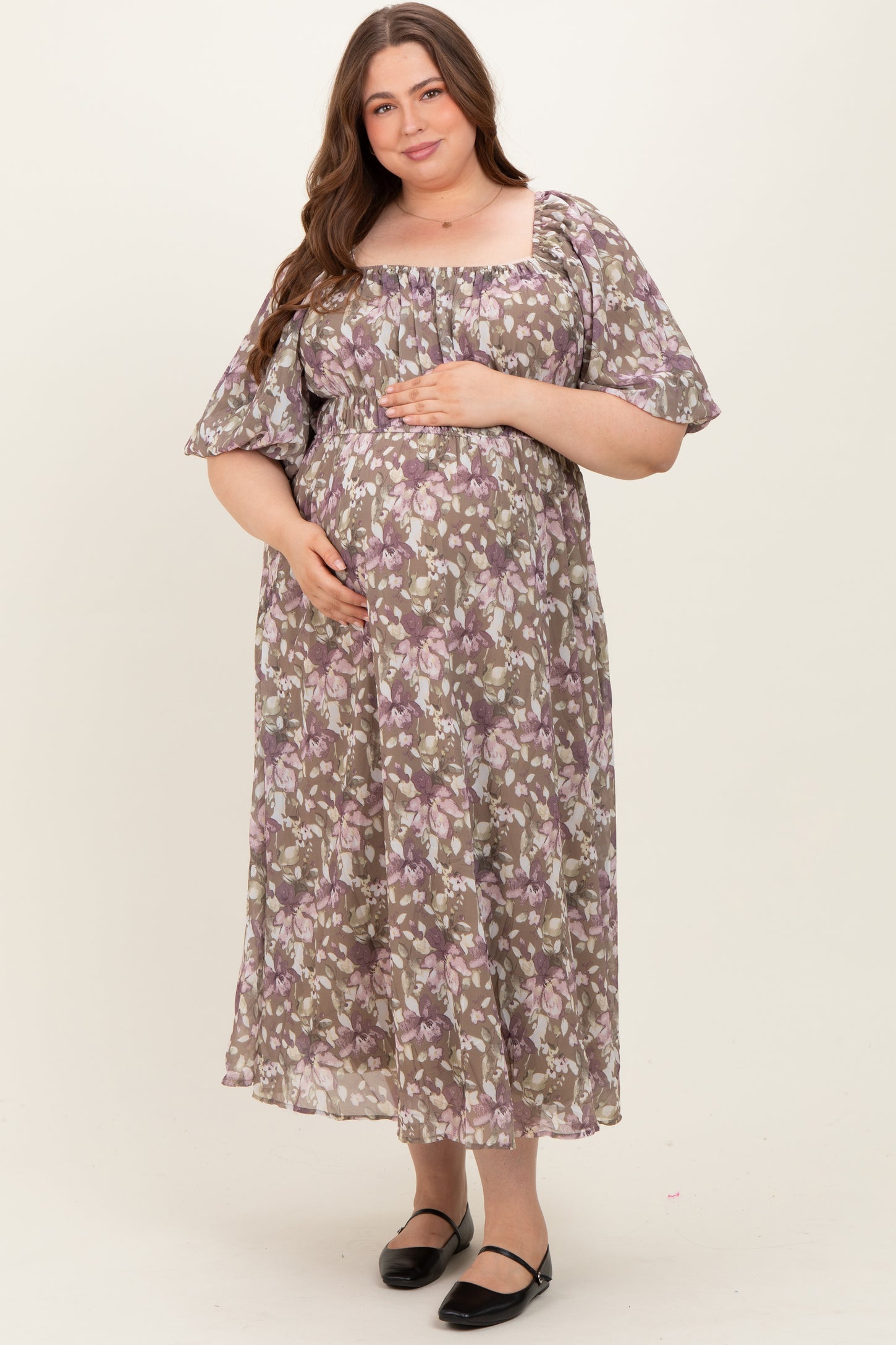 woman wearing a floral printed maternity plus maxi dress and holding her baby bump