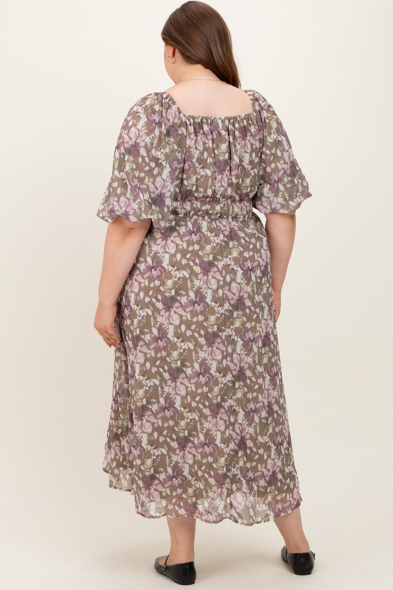 woman wearing a floral maxi maternity dress with short puff sleeves and an elasticized waist, viewed from the back