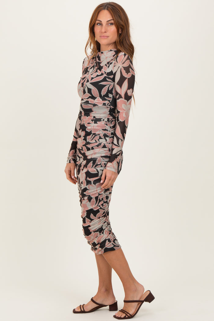 woman wearing a long sleeve floral print bodycon dress with ruched details and a mock neck, posed sideways
