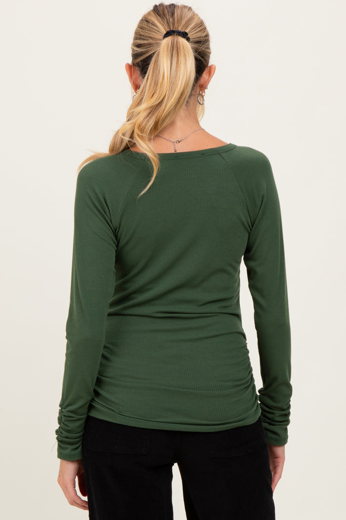 woman wearing a dark green long sleeve maternity top with ruching details at the sides