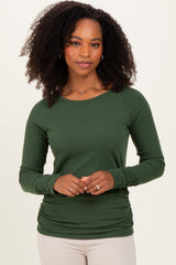 woman wearing a dark green long sleeve ribbed top with a relaxed fit and gathered side detail