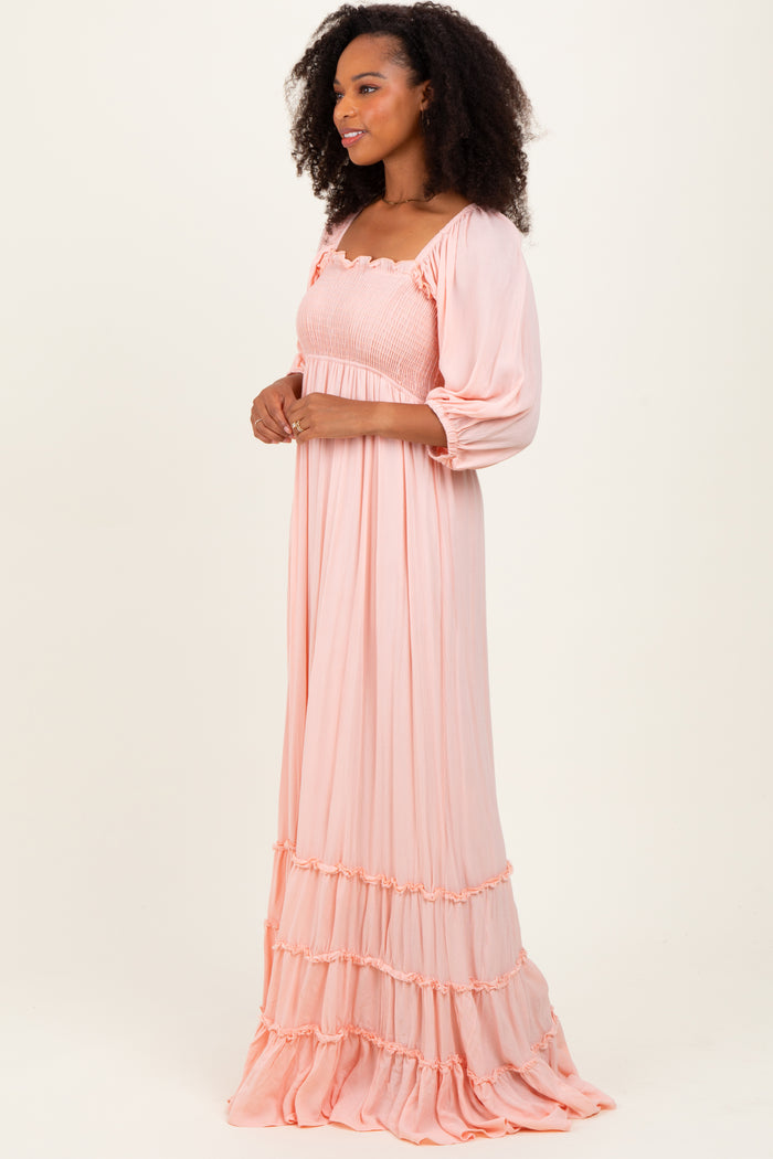 woman wearing a soft pink long maxi dress with puff sleeves and tiered ruffle details