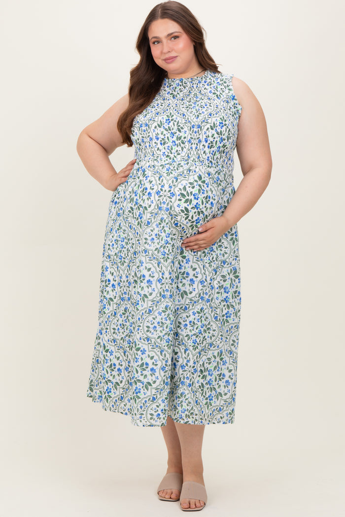 woman wearing a light blue floral sleeveless maternity dress and holding her baby bump