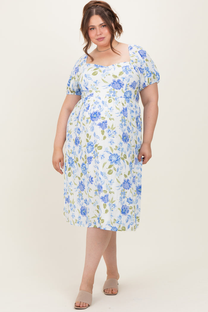 woman wearing a floral midi maternity dress in white, blue, and green with puff sleeves and a square neckline, showing her baby bump