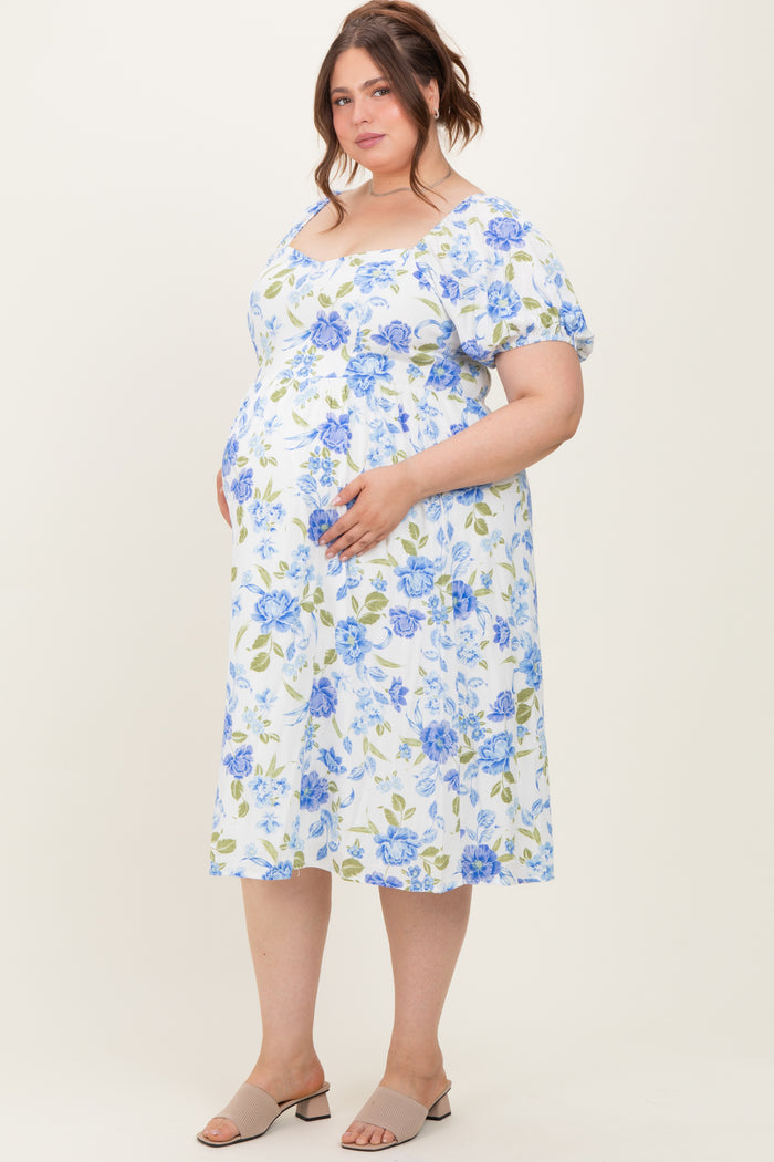woman wearing a floral print maternity plus dress with short puff sleeves and holding her baby bump