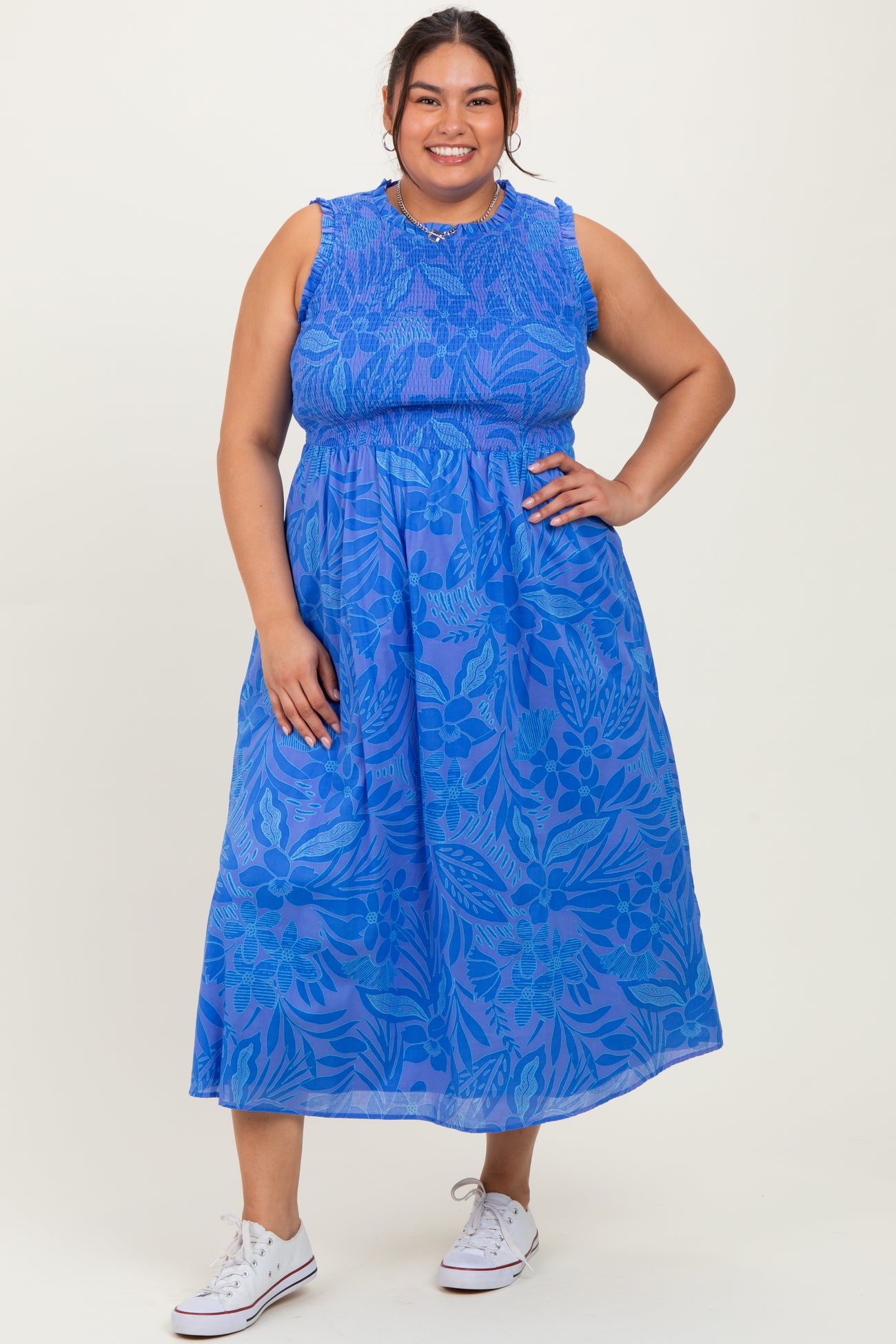 woman wearing a blue floral print plus size maxi dress with a cinched waist and relaxed fit, styled with white sneakers