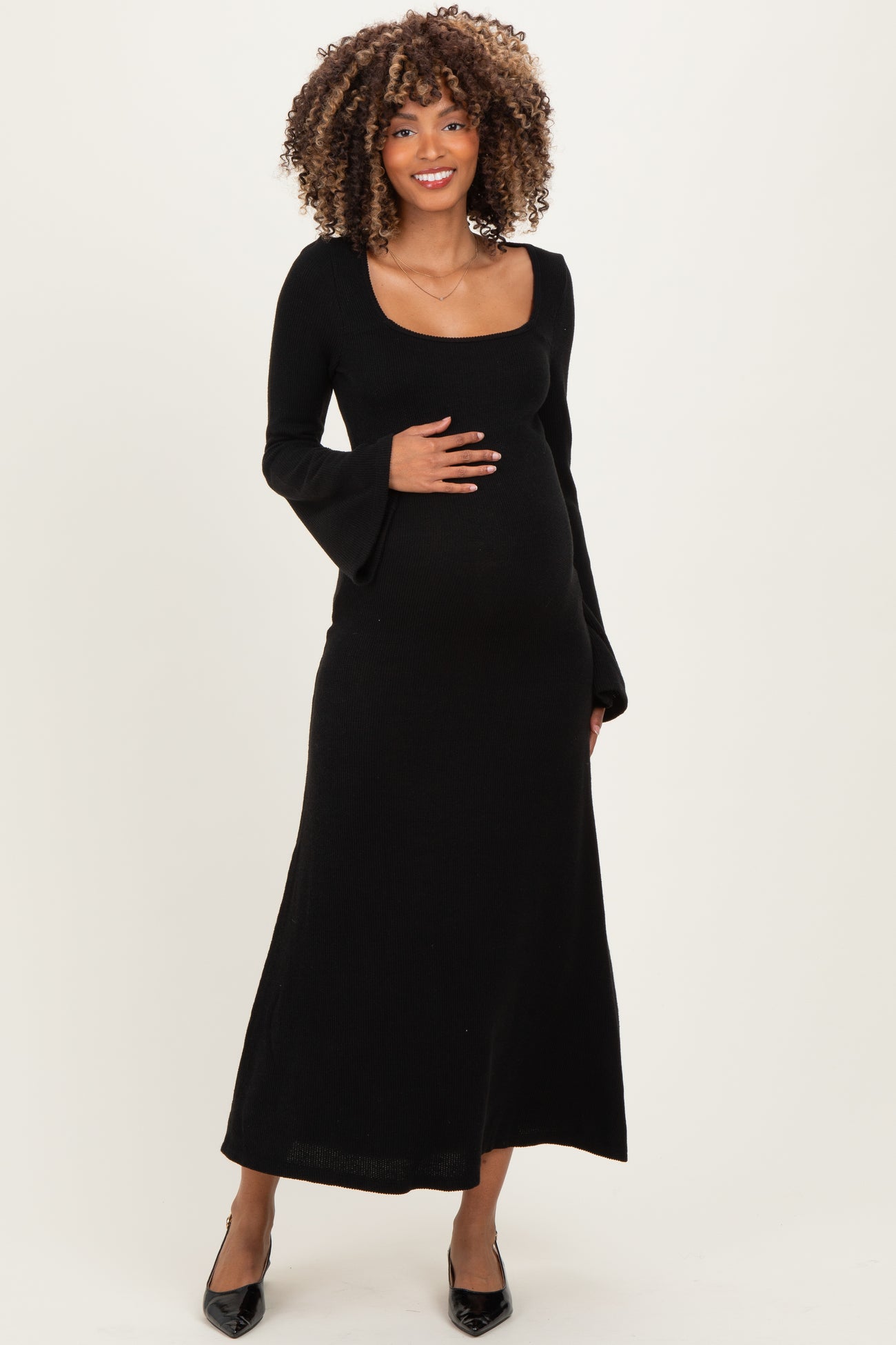 woman wearing a black long sleeve maternity dress and holding her baby bump