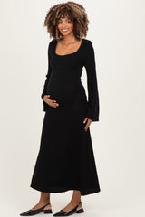 woman wearing a black long sleeve maternity dress and holding her baby bump