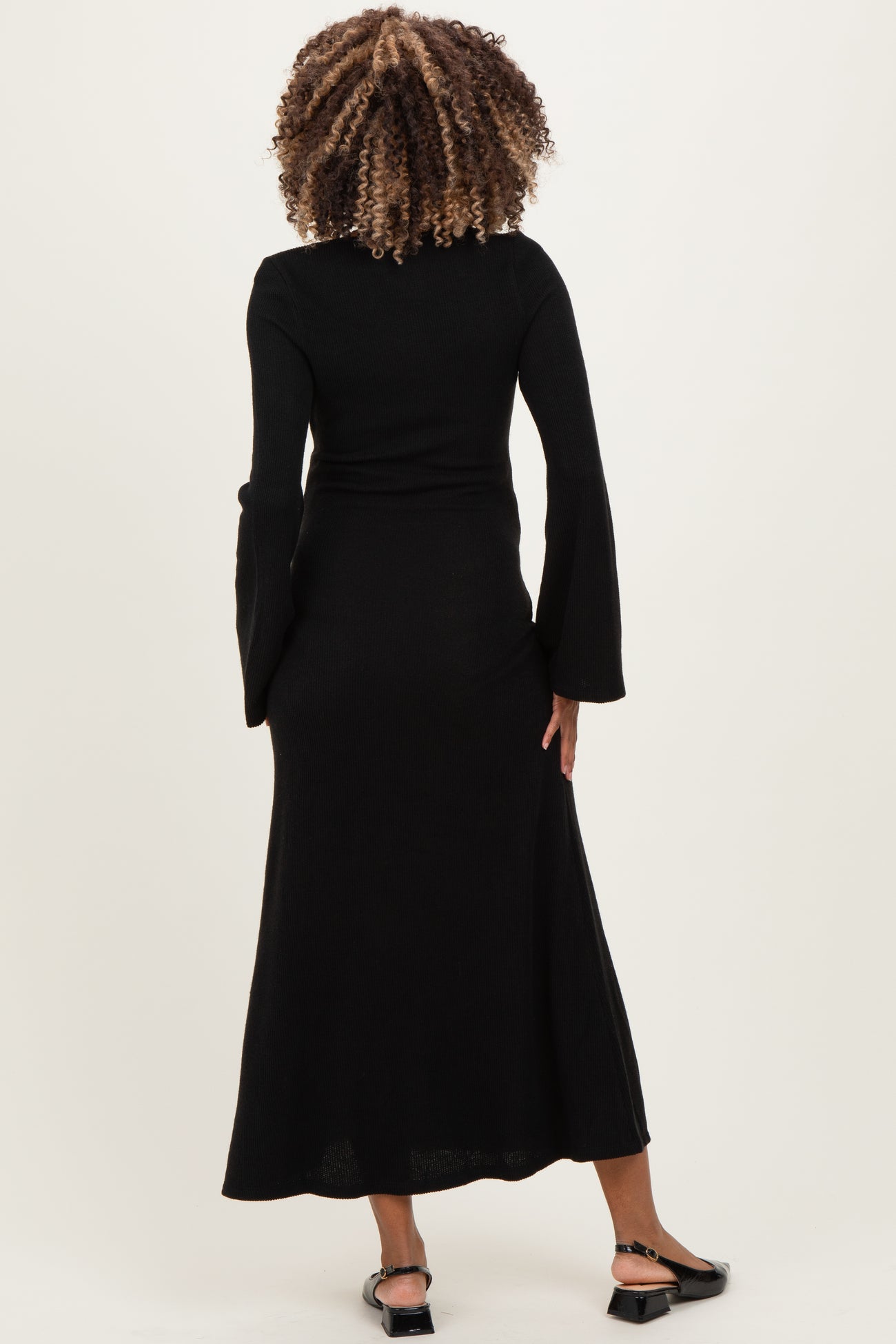 woman wearing a black long sleeve ribbed maternity dress, view from the back