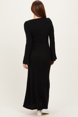 woman wearing a long black ribbed maxi dress with bell sleeves, viewed from the back