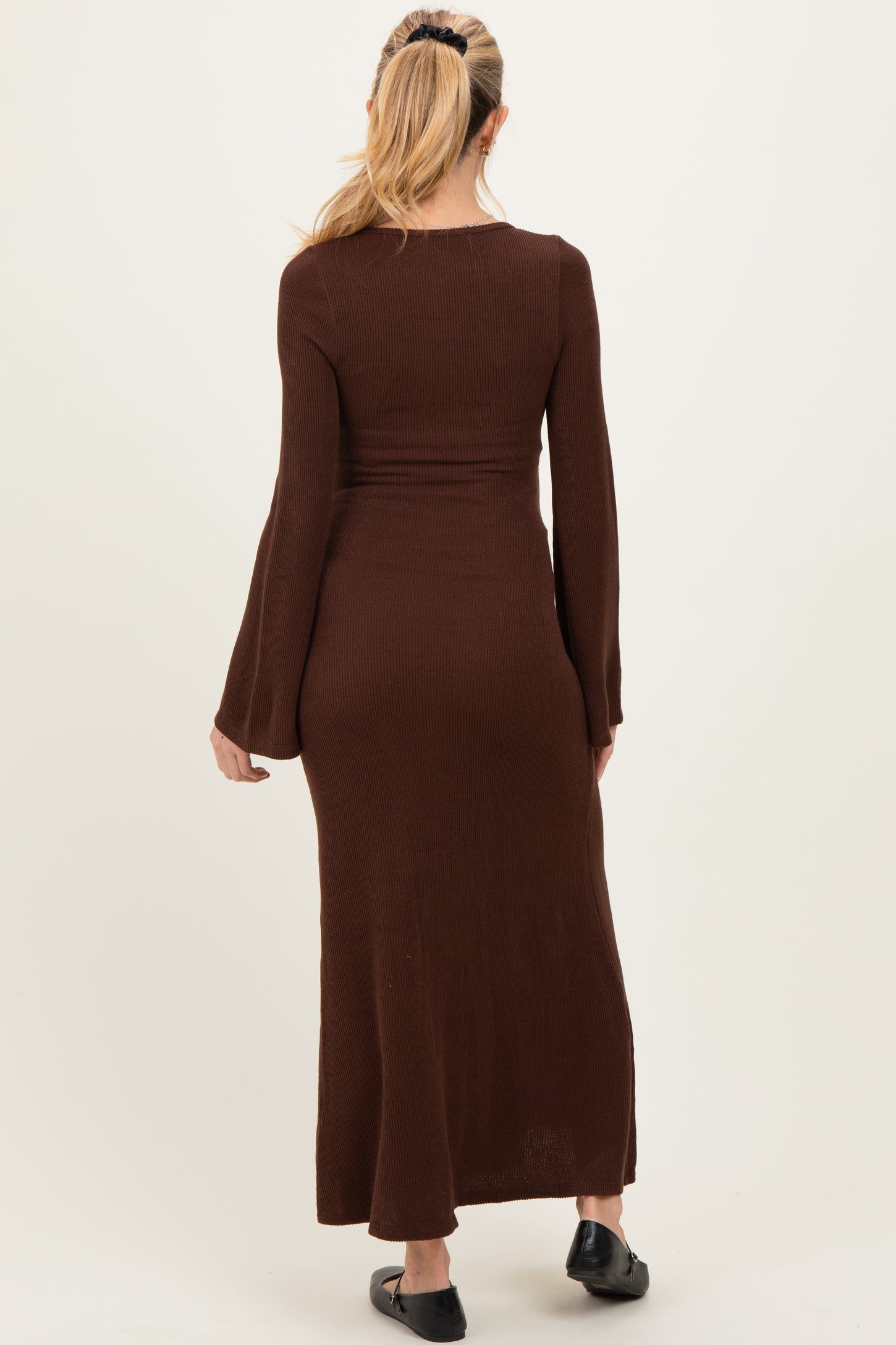 woman wearing a brown long sleeve maternity dress with a fitted silhouette and flared sleeves