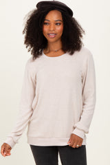 woman wearing a beige long sleeve sweater with a relaxed fit and ribbed hem, styled with a black hat