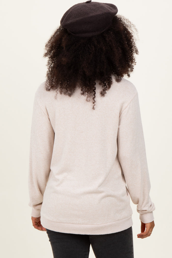 woman wearing a light beige long sleeve sweater, seen from the back, with curly hair and a black beret