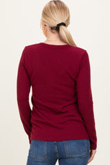 woman wearing a burgundy ribbed long sleeve top, viewed from the back, paired with blue jeans