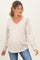 woman wearing a beige v-neck maternity sweatshirt with a pocket and a visible baby bump