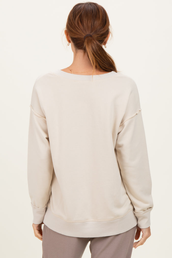 woman wearing a beige oversized sweatshirt with a relaxed fit, seen from the back