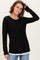 woman wearing a black long sleeve top with scalloped hem and a white inner layer showing at the neckline and bottom