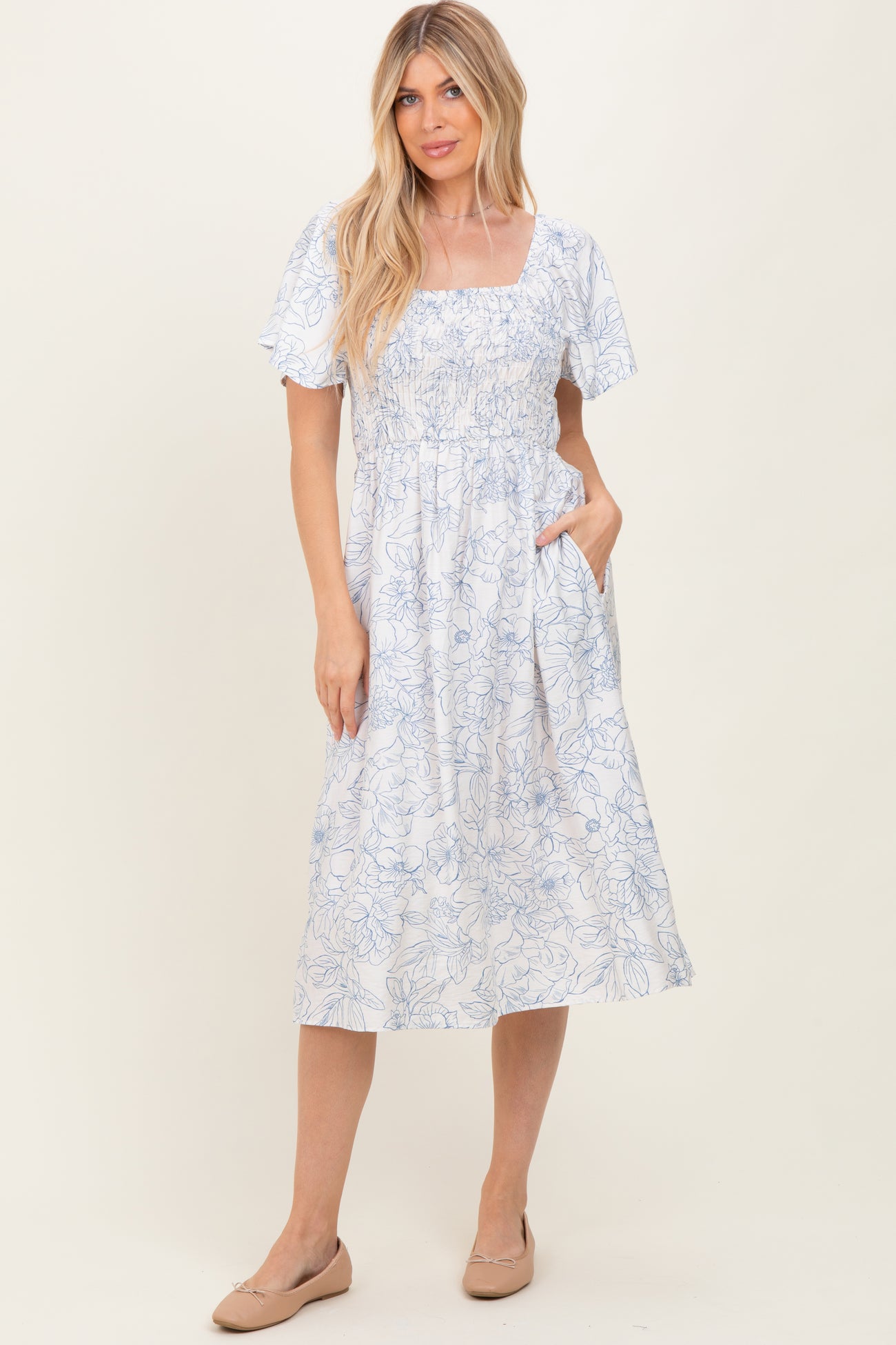 woman wearing a blue and white floral midi dress with short sleeves and pockets