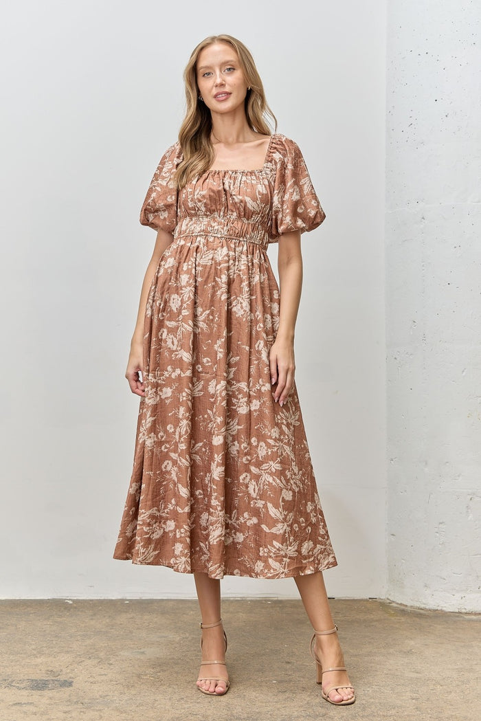 woman wearing a brown floral midi dress with puff sleeves and a smocked bodice