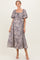 woman wearing a lavender floral maternity dress with puff sleeves and a smocked bodice