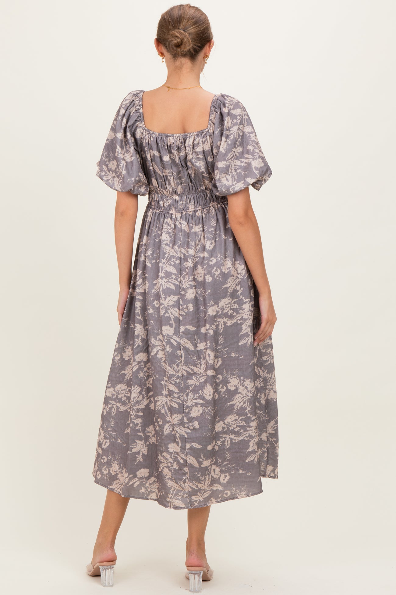 woman wearing a lavender floral maternity maxi dress with puff sleeves and a smocked back, showing a baby bump