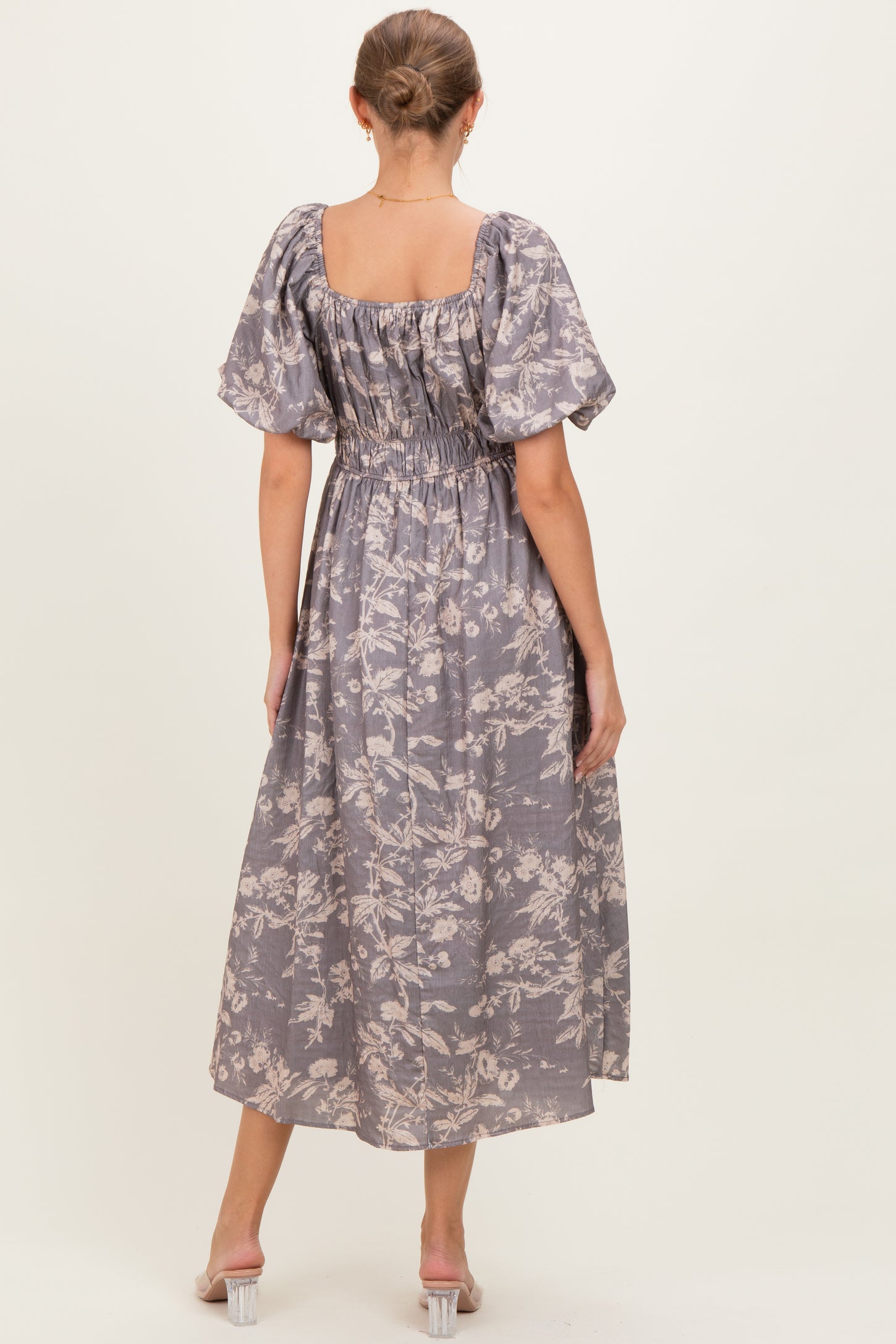 woman wearing a lavender floral maternity maxi dress with puff sleeves and a smocked back, showing a baby bump