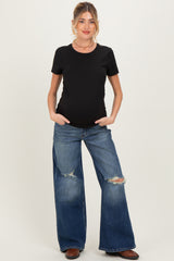 woman wearing a black maternity t-shirt and distressed wide-leg jeans, showing her baby bump