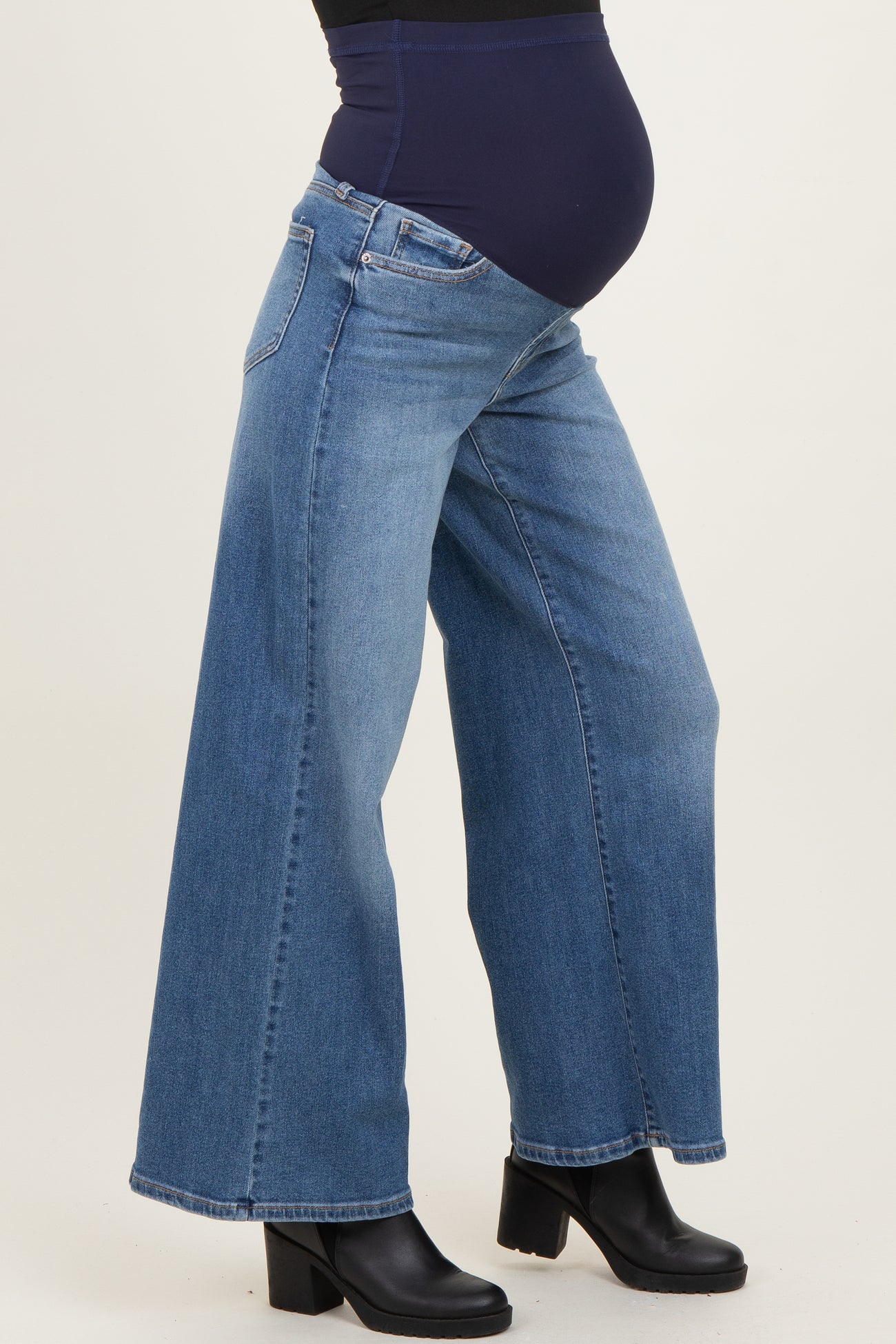 woman wearing a pair of wide-leg blue maternity jeans with a stretchy belly panel and a visible baby bump