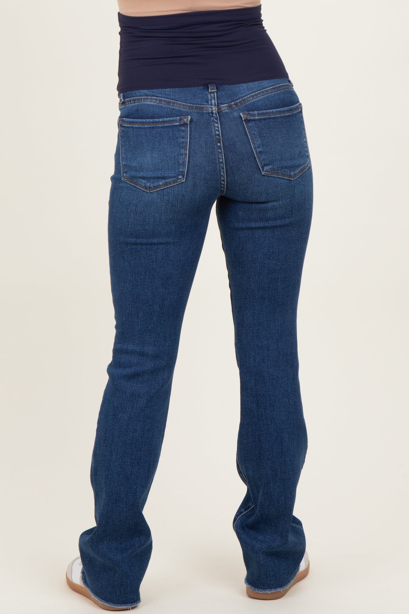 woman wearing dark blue maternity jeans with a low-rise waistband, showing the back view and a fitted style
